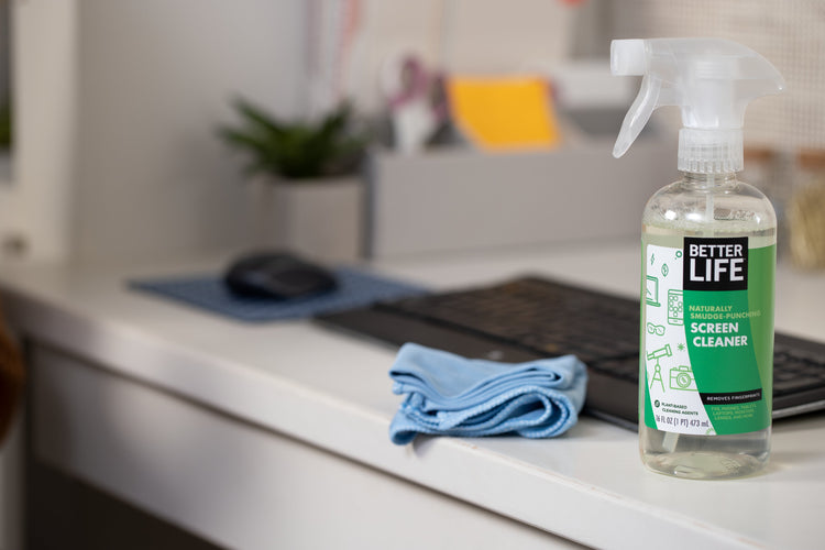 A bottle of better life cleaning spray sits on a desk.