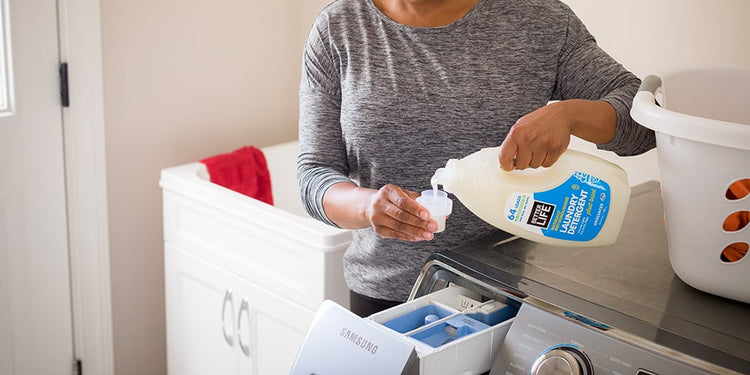 A woman pouring Better Life laundry detergent into a washing machine.
